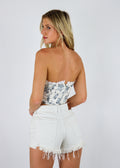 Strapless white corset tank, blue flower print. Lace trim detailing on top, small bow front center. 