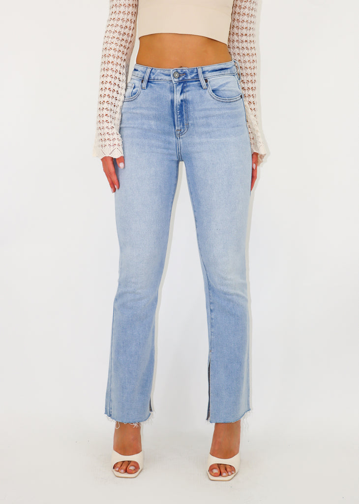 Light wash jeans features a slit hem and a high waisted fit. 