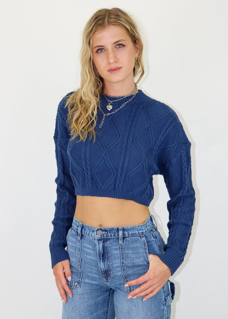 Blue cable knit sweater, cropped fit. Ribbed neckline and cuffs.