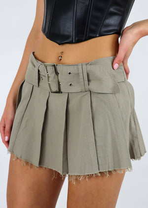 Pleated mini skirt, distressed hem, featuring a double pronged belt.