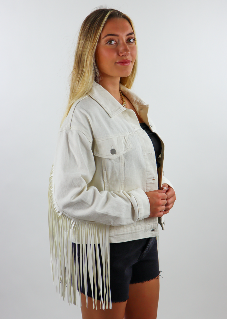 white denim jacket with silver buttons and fringe going across the entire back.